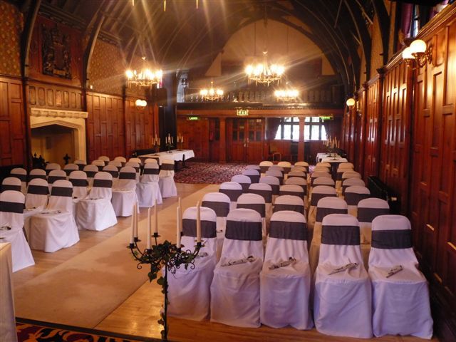 A Ceremony set up with white chair covers with a sash. A beautiful candle holder at the front of the ceremony with a view of the fire place.