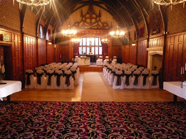 View of a ceremony at The Court House, Worsley set with white chair covers and navy sash facing the stage