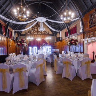 Beautifully presented dining tables for a wedding breakfast with a yellow sash on the chairs and a ceiling canopy